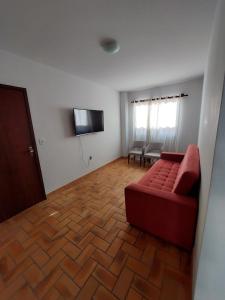 een woonkamer met een rode bank en een flatscreen-tv bij Apartamento Praia Bombas in Bombinhas