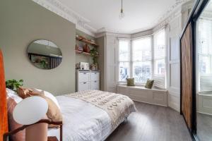 1 dormitorio con cama y espejo en Arte Stays - 2 Bed Luxurious Flat, Garden, 5min Dalston st., Parking Available, Serviced Accommodation - up to 5 ppl en Londres