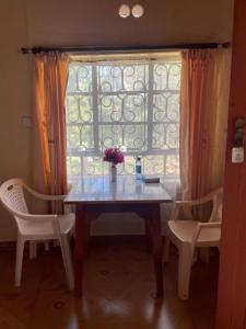 a dining room table with two chairs and a window at Jungle Green Resort, Kiutine in Meru