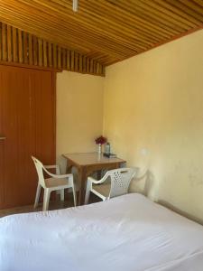 a bedroom with a bed and two chairs and a table at Jungle Green Resort, Kiutine in Meru