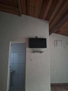 a room with a television on a wall with a shower at recanto da pedra in Paraty