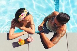 a man and a woman sitting next to a swimming pool at Le Parc at Melrose in Los Angeles