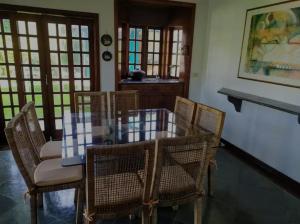 una sala da pranzo con tavolo in vetro e sedie di Casa para temporada - Guarujá - Praia Pernambuco a Guarujá