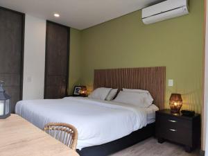 um quarto com uma grande cama branca e uma mesa de cabeceira em Tropical Confort suite Poblado welcome breakfast em Medellín