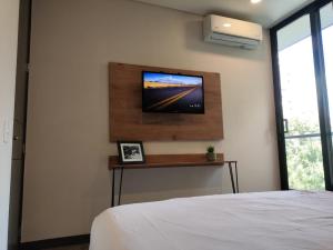 um quarto com uma cama e uma televisão na parede em Tropical Confort suite Poblado welcome breakfast em Medellín