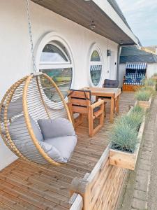 een veranda met een schommel en een tafel en stoelen bij Strandhus Windjammer in Kalifornien