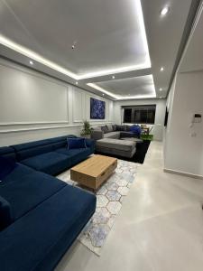 een woonkamer met blauwe banken en een tafel bij Appartement Bouznika Plage in Bouznika