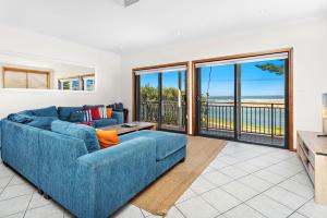 a living room with a blue couch and sliding glass doors at Allure On Seven Mile Beach Gerroa in Gerroa