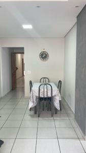 a table and chairs in a room with a clock on the wall at Apartamento praia Aviação in Praia Grande