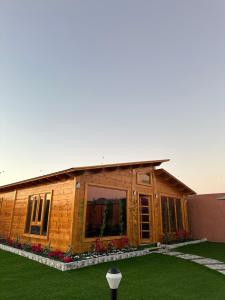 a log cabin with a large window and green grass at كوخ السعاده happiness hut in Thuwal