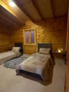 1 dormitorio con 2 camas en una cabaña de madera en كوخ السعاده happiness hut, en Thuwal