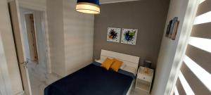 ein kleines Schlafzimmer mit einem blauen Bett und gelben Kissen in der Unterkunft 2-bed apartment in Mellieha in Mellieħa
