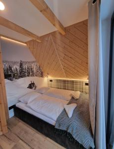 un lit dans une chambre avec un plafond en bois dans l'établissement FILIPOWE CHATY, à Kościelisko