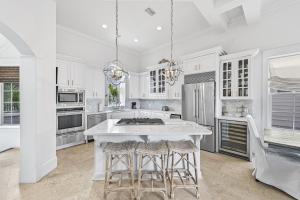 a kitchen with white cabinets and a white island with bar stools at 15 Mathis Cove in Inlet Beach