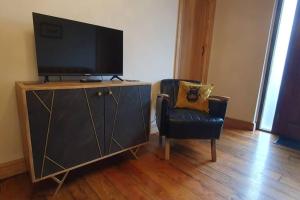 a television sitting on top of a cabinet with a chair at 2 bed gem on the riverbank 15 mins from Cardiff centre in Cardiff
