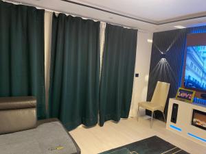 a living room with green curtains and a couch at GraceHomes (Entry to Blackforest) in Jettingen
