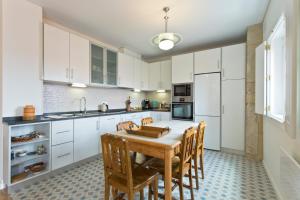 a kitchen with white cabinets and a wooden table and chairs at Estrela de Gaia Apartments in Vila Nova de Gaia