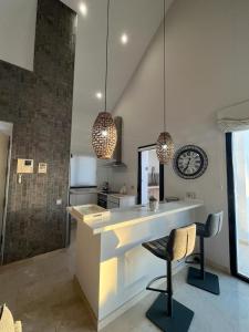 a kitchen with a counter and two chairs and a clock at Penthouse Golf lujo, Perla Sol 1 in Vera