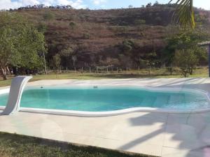 een zwembad in een tuin naast een heuvel bij Sítio no interior de MG, lugar de sossego e paz! in São Domingos do Prata