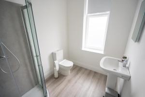 a white bathroom with a toilet and a sink at The Bank Apartment Irvinestown in Irvinestown