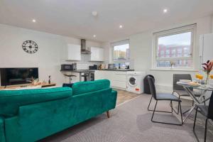 a living room with a green couch and a kitchen at 3 Beds - Perfect for Family & Work Relocations in Leeds