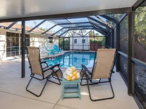 Un patio con dos sillas y una piscina. en Alligator Escape - Heated pool haven just minutes from Venice beaches, en Venice