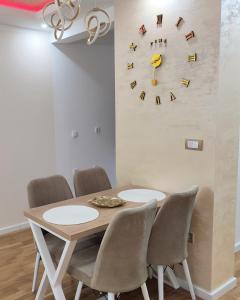 a dining room table with chairs and a clock on the wall at Apartman Aleksej Valjevo in Valjevo