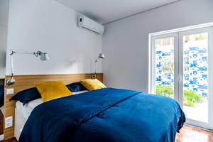 a bedroom with a large blue bed with yellow pillows at Historic Town Cascais Modern Apartment in Cascais