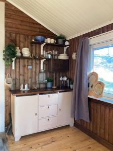 una cocina con armarios blancos y una ventana en Typisk norsk off-grid hytte opplevelse, en Levanger
