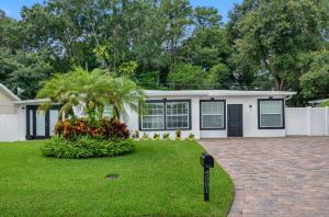 a white house with a palm tree in a yard at Tranquil Paradise 4BR - 2 Miles To Tampa Bucs Stadium in Tampa