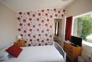 a bedroom with a bed with a floral wallpaper at The Curraghmore in Shanklin