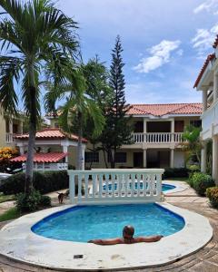 un hombre tendido en una piscina frente a una casa en Palma Real BAVARO Beach, en Punta Cana