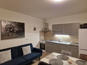 sala de estar con sofá azul y cocina en Apartmán NH Stables, en Nýřany