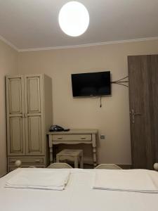 a room with two beds and a desk and a television at Alex Bar APARTMENTS SARAKINIKO in Parga
