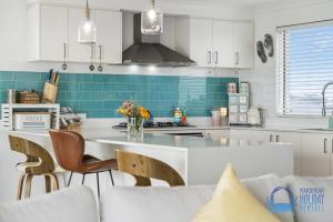 una cocina con armarios blancos y azulejos azules en Luxury Sunset & Surf in Halls Head en Wannanup