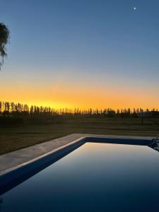 a swimming pool with the sunset in the background at Las Potrancas cabaña in General Alvear