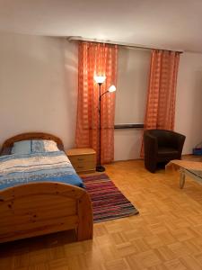 a bedroom with a bed and a lamp and a chair at Premium Handwerker Zimmer in Balingen