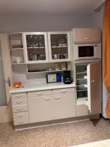 a kitchen with white cabinets and a microwave at Premium Handwerker Zimmer in Balingen