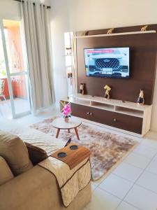 a living room with a couch and a flat screen tv at Pier Jacuípe Residencial in Camaçari