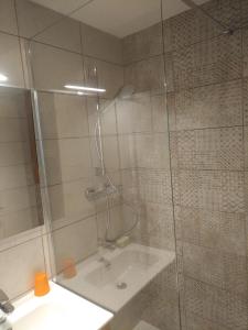 una ducha con una puerta de cristal junto a un lavabo en appartement en duplex dans un chalet typique, en Valloire