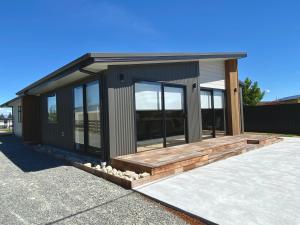 ein kleines Haus mit einer Holzterrasse auf einer Auffahrt in der Unterkunft Executive Comfort in Twizel