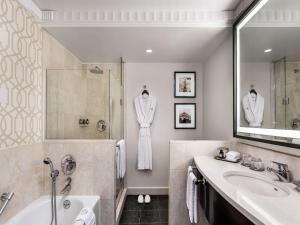 a bathroom with a tub and a sink and a robe on the wall at Sofitel Lafayette Square Washington DC in Washington, D.C.