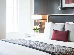 a bedroom with a white bed with a red pillow at Sofitel Lafayette Square Washington DC in Washington