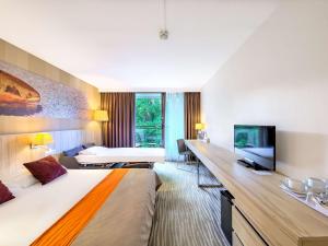 ein Hotelzimmer mit einem großen Bett und einem TV in der Unterkunft Mercure Gdańsk Posejdon in Danzig