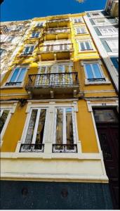 a tall yellow building with windows and a balcony at Suites Luciano Cordeiro in Lisbon
