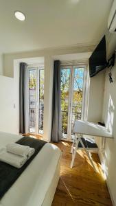 a bedroom with a bed and a television and a desk at Suites Luciano Cordeiro in Lisbon