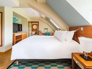 a bedroom with a white bed and a tv at Sofitel Grand Sopot in Sopot