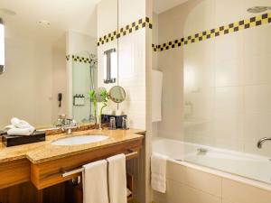 a bathroom with a tub and a sink and a bath tub at Sofitel Grand Sopot in Sopot