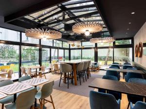 a restaurant with tables and chairs and windows at ibis Paris Bastille Faubourg St Antoine in Paris