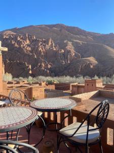 two tables and chairs on a balcony with a mountain at Tafsut dades guesthouse stay with locals in Tamellalt